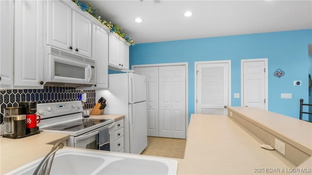 kitchen featuring sink, white cabinets, and white appliances