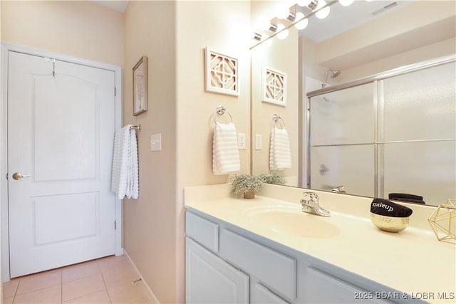 bathroom with a shower with door, vanity, and tile patterned floors