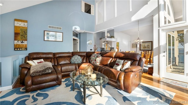 living room featuring a notable chandelier, light hardwood / wood-style flooring, and vaulted ceiling