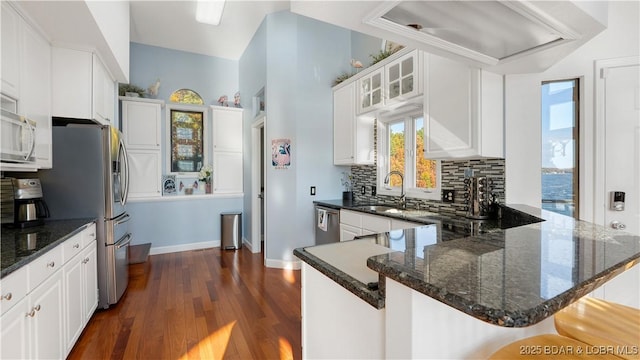 kitchen with appliances with stainless steel finishes, tasteful backsplash, sink, white cabinets, and kitchen peninsula