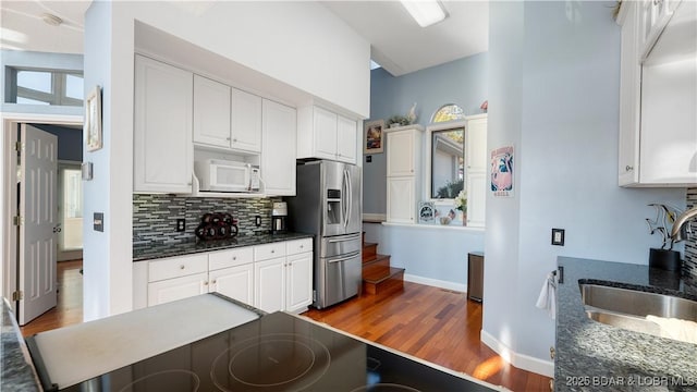 kitchen featuring sink, backsplash, stainless steel refrigerator with ice dispenser, white cabinets, and dark hardwood / wood-style flooring