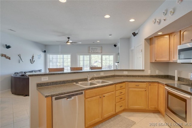 kitchen with sink, light tile patterned floors, appliances with stainless steel finishes, kitchen peninsula, and light brown cabinets