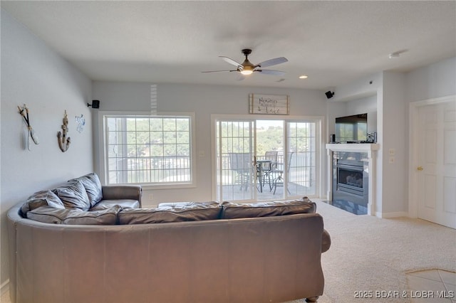 carpeted living room with a tiled fireplace and ceiling fan