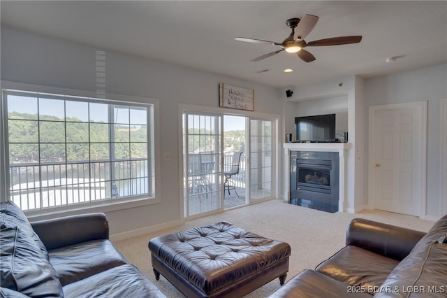 carpeted living room featuring a fireplace and ceiling fan