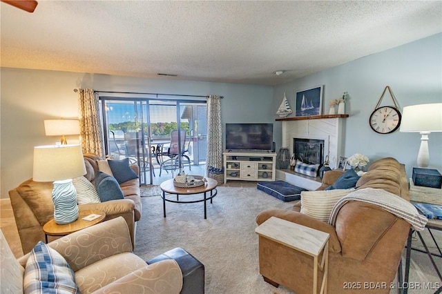 living room featuring a tile fireplace, a textured ceiling, and carpet flooring