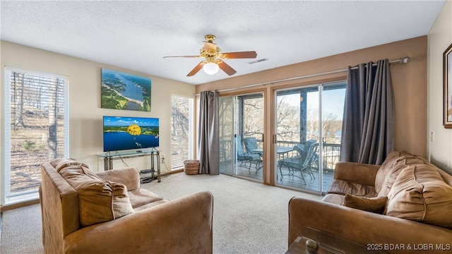 carpeted living room featuring ceiling fan, plenty of natural light, and a textured ceiling