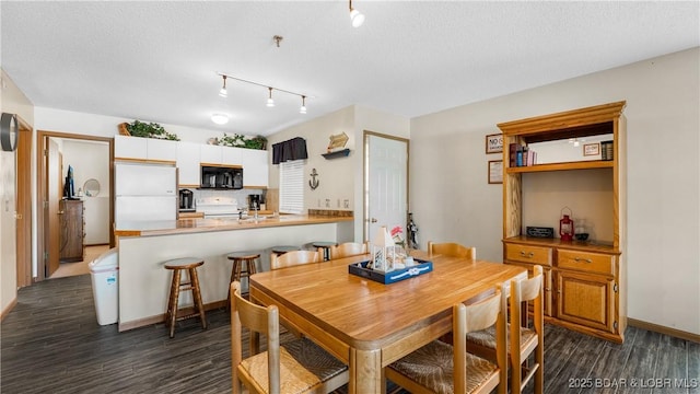 dining space featuring dark wood-type flooring and a textured ceiling