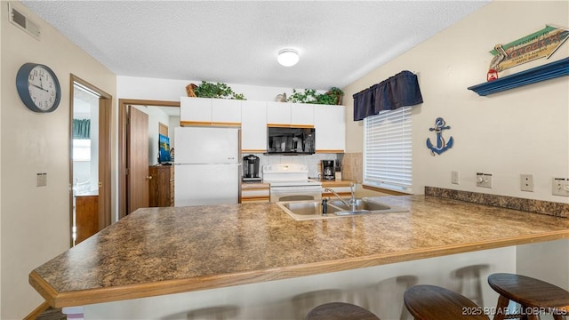 kitchen with white cabinetry, sink, a kitchen breakfast bar, kitchen peninsula, and white appliances