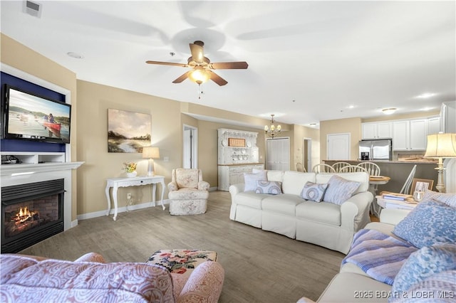 living room featuring wood-type flooring and ceiling fan with notable chandelier