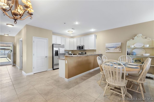 kitchen featuring light tile patterned flooring, white cabinetry, hanging light fixtures, appliances with stainless steel finishes, and kitchen peninsula