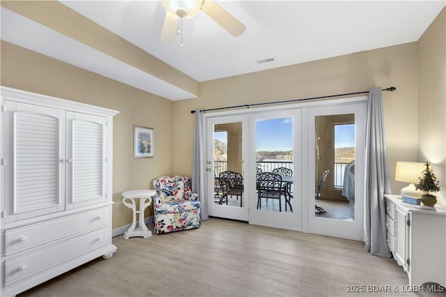 living area with french doors, ceiling fan, and light hardwood / wood-style flooring