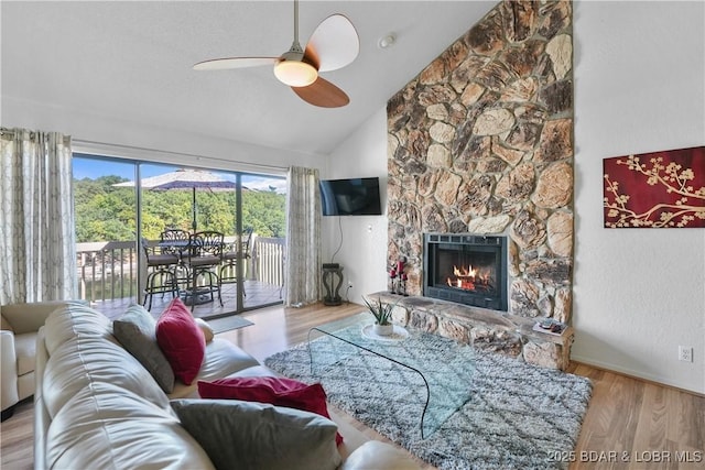 living room featuring ceiling fan, a fireplace, high vaulted ceiling, and light hardwood / wood-style flooring