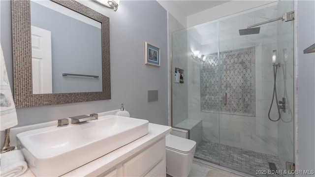 bathroom featuring a shower with door, vanity, and toilet