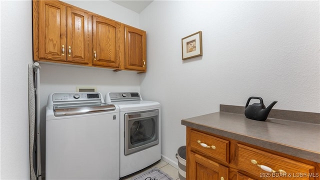 clothes washing area with cabinets and washing machine and clothes dryer