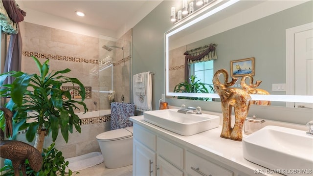 bathroom with vanity, toilet, and tiled shower