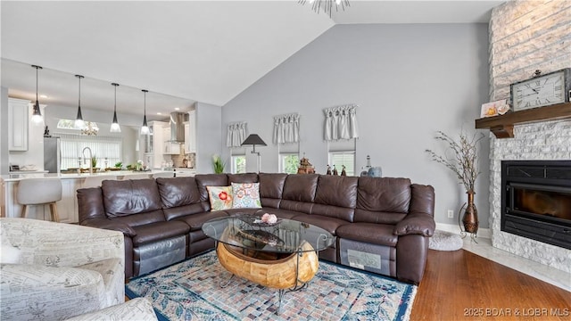 living room with dark wood-type flooring, a fireplace, high vaulted ceiling, and a wealth of natural light