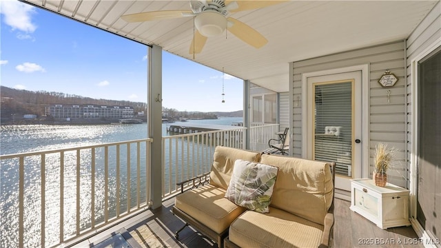 balcony with ceiling fan and a water view