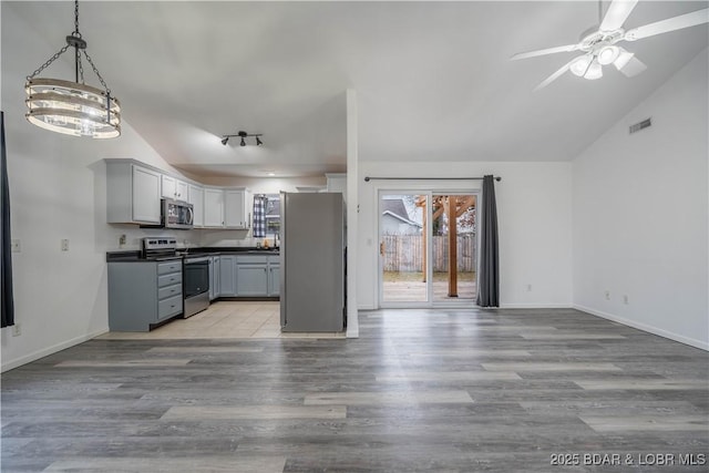 kitchen featuring gray cabinets, appliances with stainless steel finishes, decorative light fixtures, vaulted ceiling, and light wood-type flooring