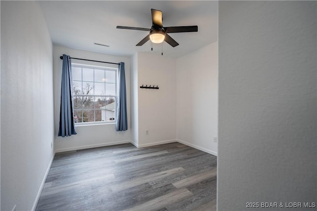 spare room featuring dark wood-type flooring and ceiling fan