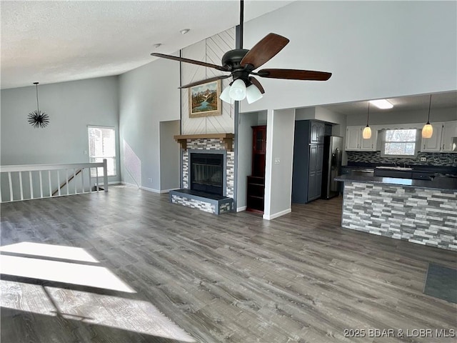 unfurnished living room featuring dark wood-type flooring, sink, vaulted ceiling, a textured ceiling, and ceiling fan