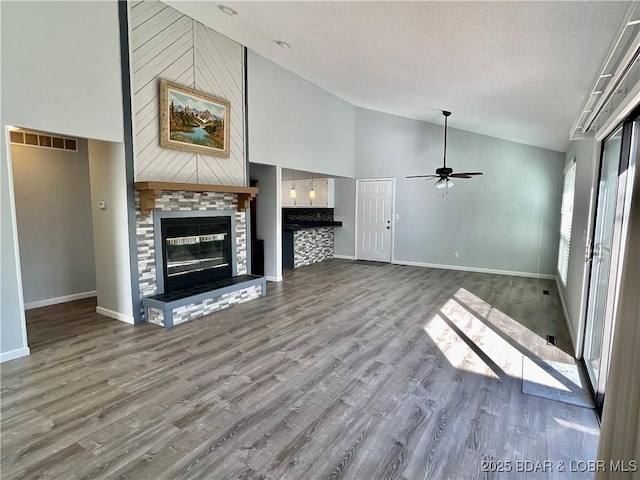 unfurnished living room with hardwood / wood-style floors, a textured ceiling, high vaulted ceiling, and ceiling fan