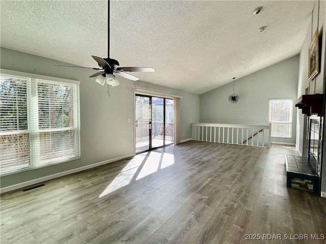 unfurnished living room with hardwood / wood-style flooring, vaulted ceiling, and a textured ceiling