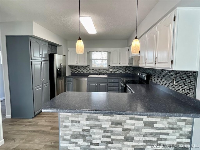 kitchen featuring sink, decorative light fixtures, kitchen peninsula, and appliances with stainless steel finishes