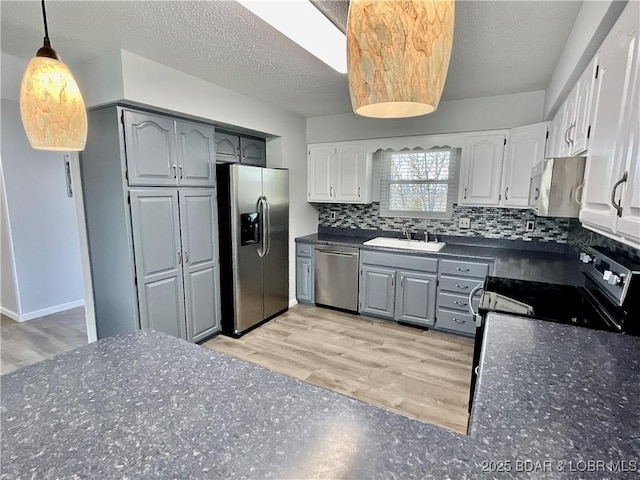 kitchen featuring tasteful backsplash, stainless steel appliances, gray cabinets, and sink