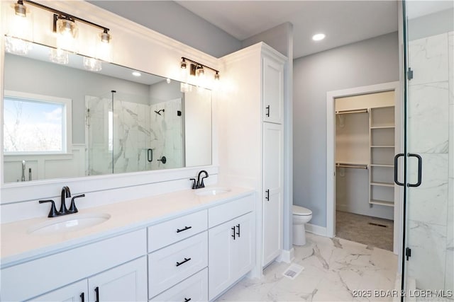 bathroom featuring vanity, a shower with door, and toilet