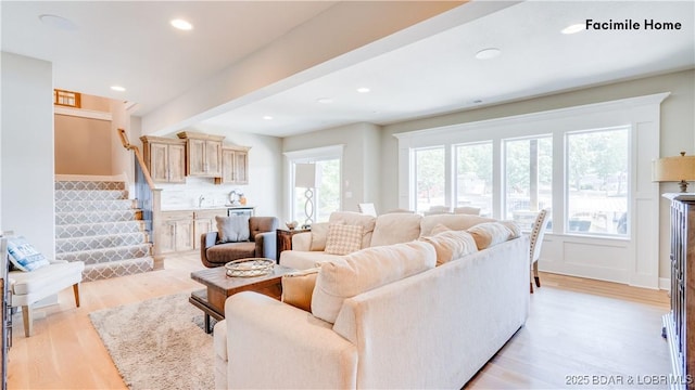 living room with beam ceiling, sink, and light hardwood / wood-style flooring