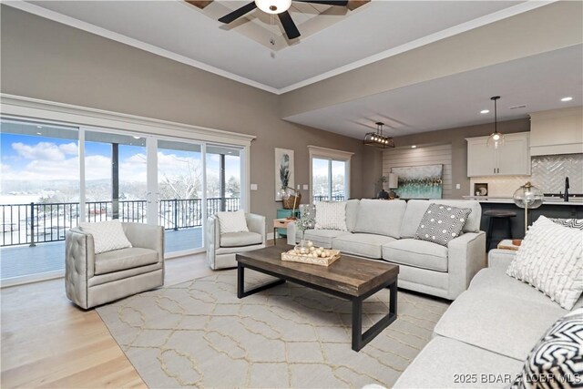 living room with ornamental molding, sink, ceiling fan, and light wood-type flooring