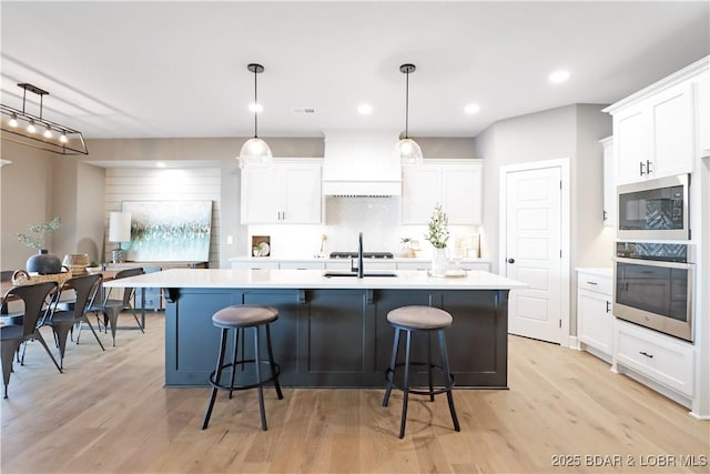 kitchen featuring decorative light fixtures, white cabinets, and appliances with stainless steel finishes