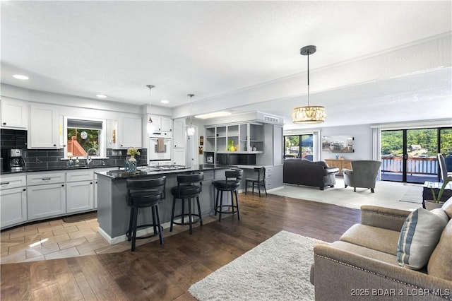 kitchen with hanging light fixtures, white cabinetry, and dark wood-type flooring