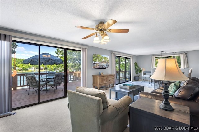 carpeted living room featuring ceiling fan, a textured ceiling, and a healthy amount of sunlight