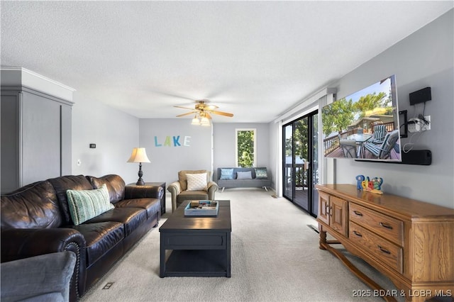 living room with ceiling fan, light carpet, and a textured ceiling