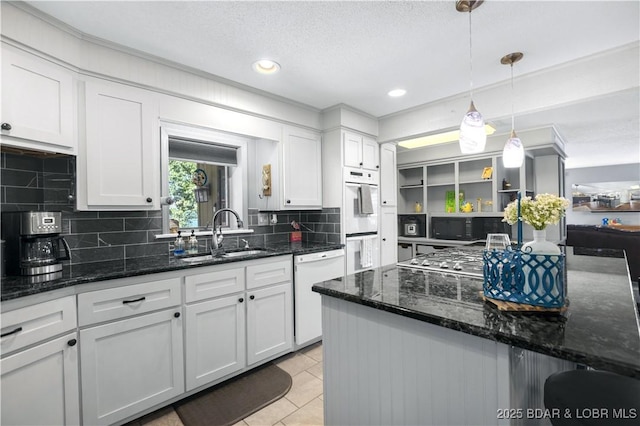 kitchen featuring sink, white appliances, dark stone counters, and white cabinets