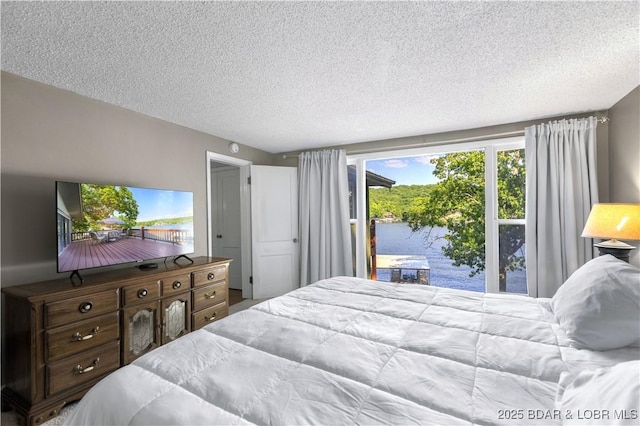 bedroom with a textured ceiling and a water view