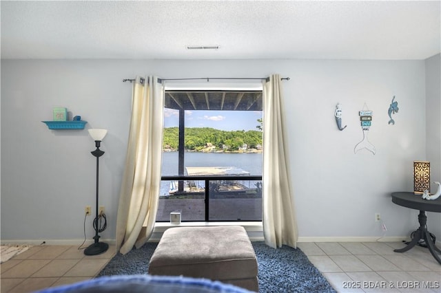 doorway to outside featuring a water view, light tile patterned floors, and a textured ceiling