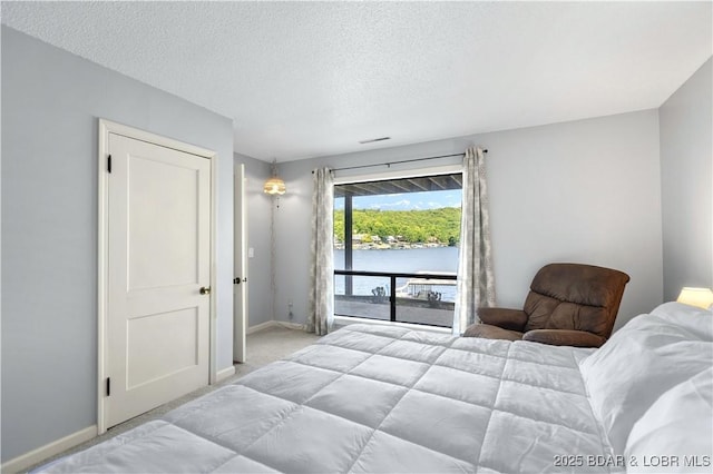 carpeted bedroom featuring a water view, a textured ceiling, and access to outside