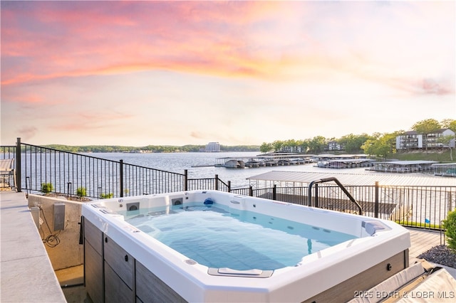 patio terrace at dusk with a hot tub and a water view