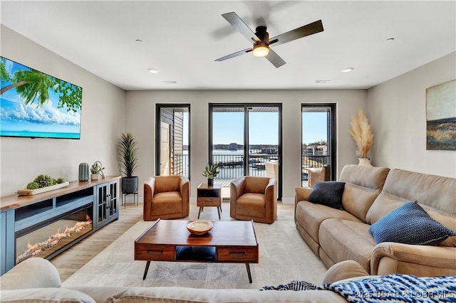 living room with a water view, ceiling fan, and light hardwood / wood-style floors