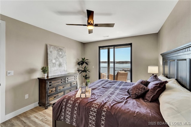 bedroom with access to exterior, light hardwood / wood-style flooring, ceiling fan, and a water view