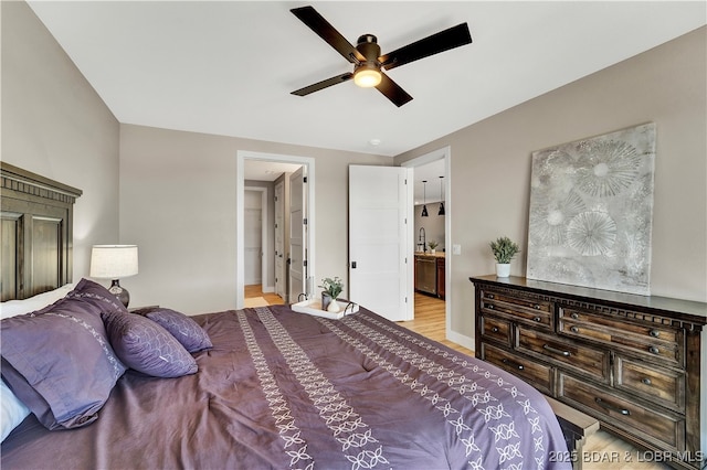 bedroom featuring ceiling fan, ensuite bathroom, sink, and light wood-type flooring