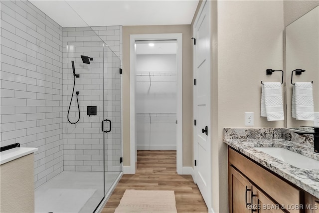 bathroom with hardwood / wood-style flooring, vanity, and a shower with shower door