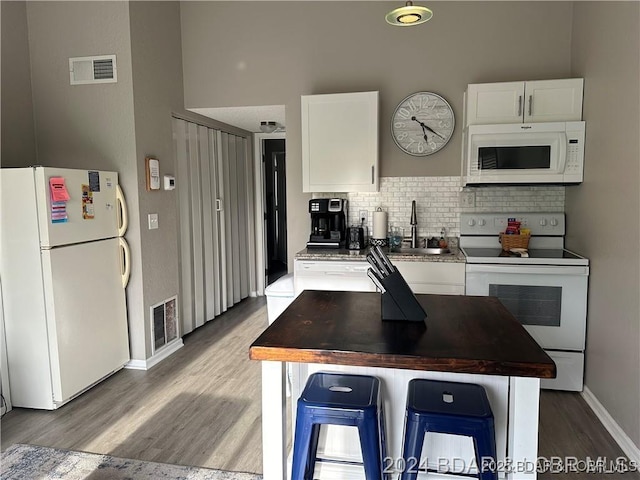 kitchen with sink, white appliances, white cabinetry, backsplash, and light hardwood / wood-style floors