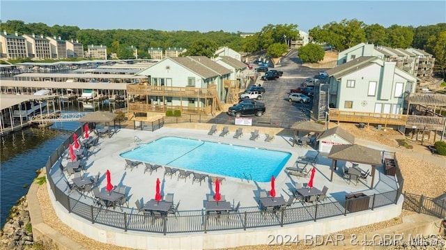 view of swimming pool featuring a water view, fence, and a patio