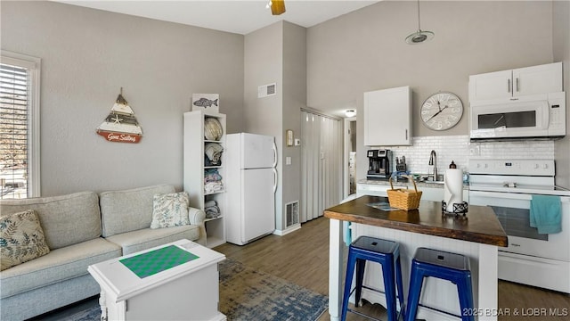 kitchen featuring white appliances, visible vents, wooden counters, and open floor plan