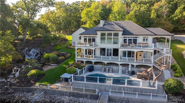 back of house featuring a balcony, a pool with hot tub, and a patio