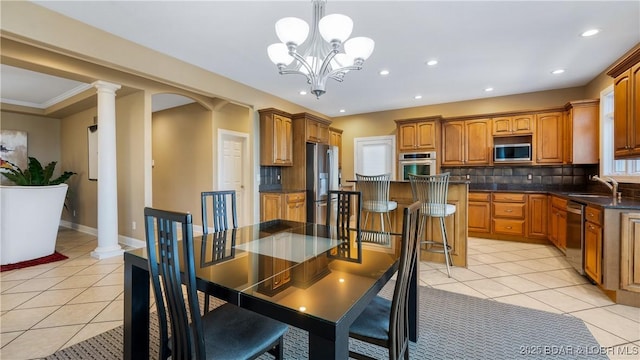 tiled dining area with sink, a notable chandelier, ornamental molding, and decorative columns