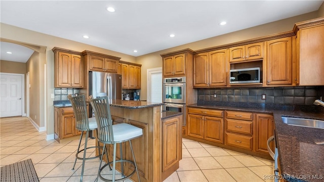 kitchen with appliances with stainless steel finishes, a center island, sink, and light tile patterned floors